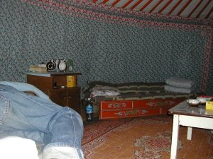 Jurtta sisältä. Seinät ovat päällystetty kankailla ja huonekalut kiertävät seiniä. 