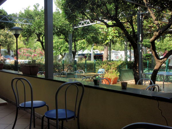 Leirintäalueemme oleskelu- tai ravintolakatosta. Vieressä oli uima-alla, joka ei ollut maahan upotettu, vaan jonne meni maatasolta tikkaat. Kälisevät ranskalaisteinit vähän hermostuttivat täällä istuskellessa. Useimmilla muillahan on leirintäalueilla omat pöydät ja tuolit mukana, mutta ei meillä reppumatkalaisilla.