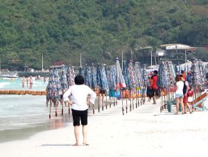 Rannalla törröttäviä suljettuja auringonvarjoja. 