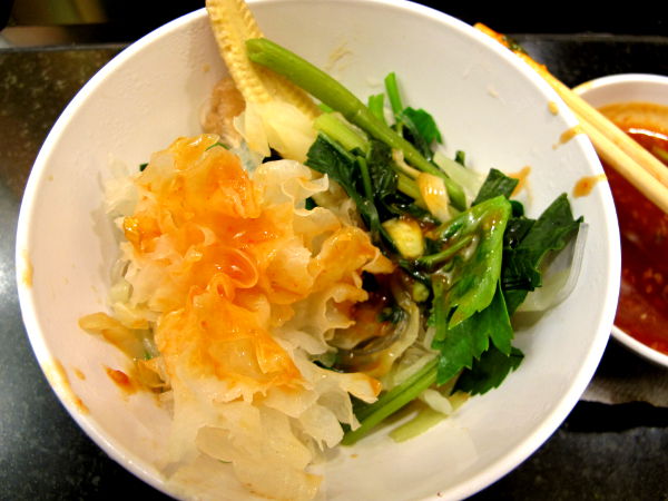 Sukista poimittua valkoista ja lehtevää tremella fuciformis -sientä, jonka päällä on oranssia dippisoossia. Alla ainakin vesipinaattia, lehtiselleriä ja minimaissia. 