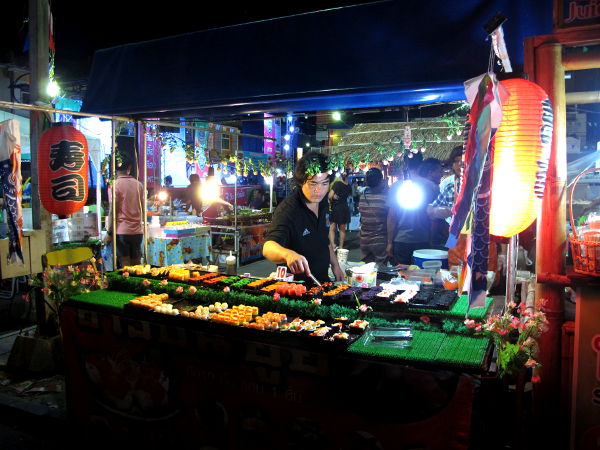 Sushikoju viikonlopputorilla. Näitä kojuja näkee yleensä aina Thaimaan iltatoreilla ja niistä löytyy yleensä vegaanisena ainakin wakame-merileväsalaatilla päällystettyjä sushirullia 5 tai 10 bahtin kappalehintaan. 