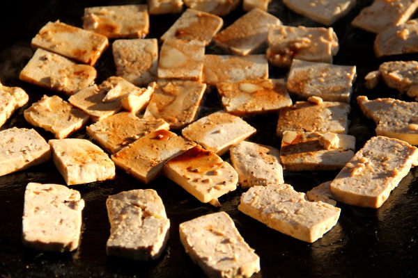 Sinappitofut paistumassa. Ohuemmat ja pienemmät viipaleet ovat Jalotofua ja paksummat ja isommat viipaleet ovat Alpron tofua. Alpron tofu murenee helpommin, joten paistaessa se on parempi viipaloida paksummaksi.