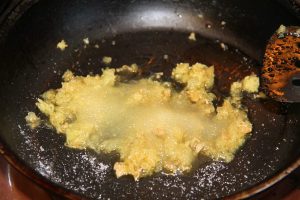 Tuoretta valkosipulia ja inkivääriä paistumassa pannulla sokerin ja suolan kera. 