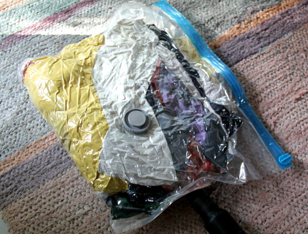 Ilmattomaksi pölynimurilla imaistu vakuumipussi, jossa on noin kymmenen isoa t-paitaa ja kolmet ohuet pitkät kangashousut. 