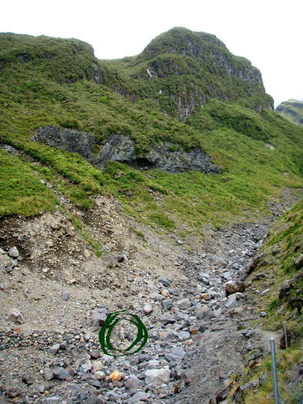 Vuoren rinnettä, ympyröitynä näkyy pienenä ihminen. 