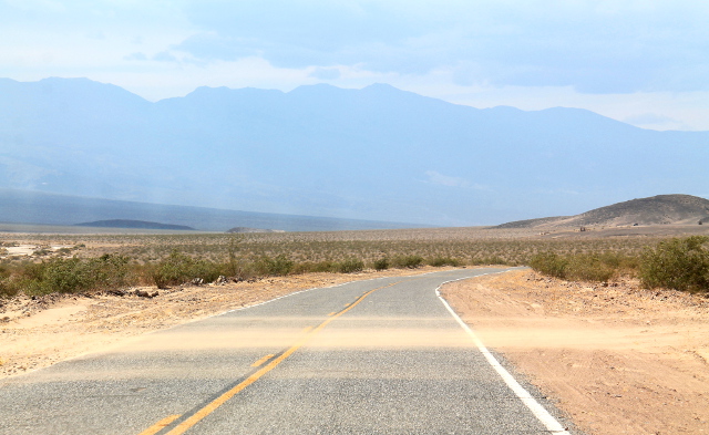 Death Valleyssa tuuli. Tässä tuuli työntää hiekkaa tien yli. 