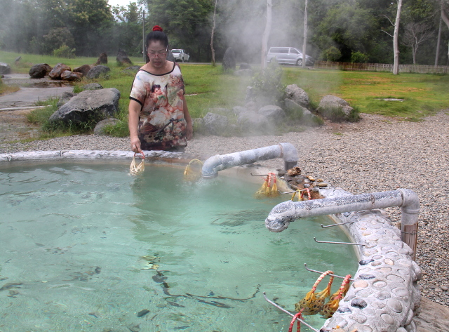 Nainen keittämässä munia kuumassa lähteessä.