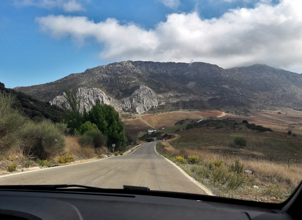 päällystetty ajotie kuvattuna auton etuikkunasta ja edessä näkyy vuori.